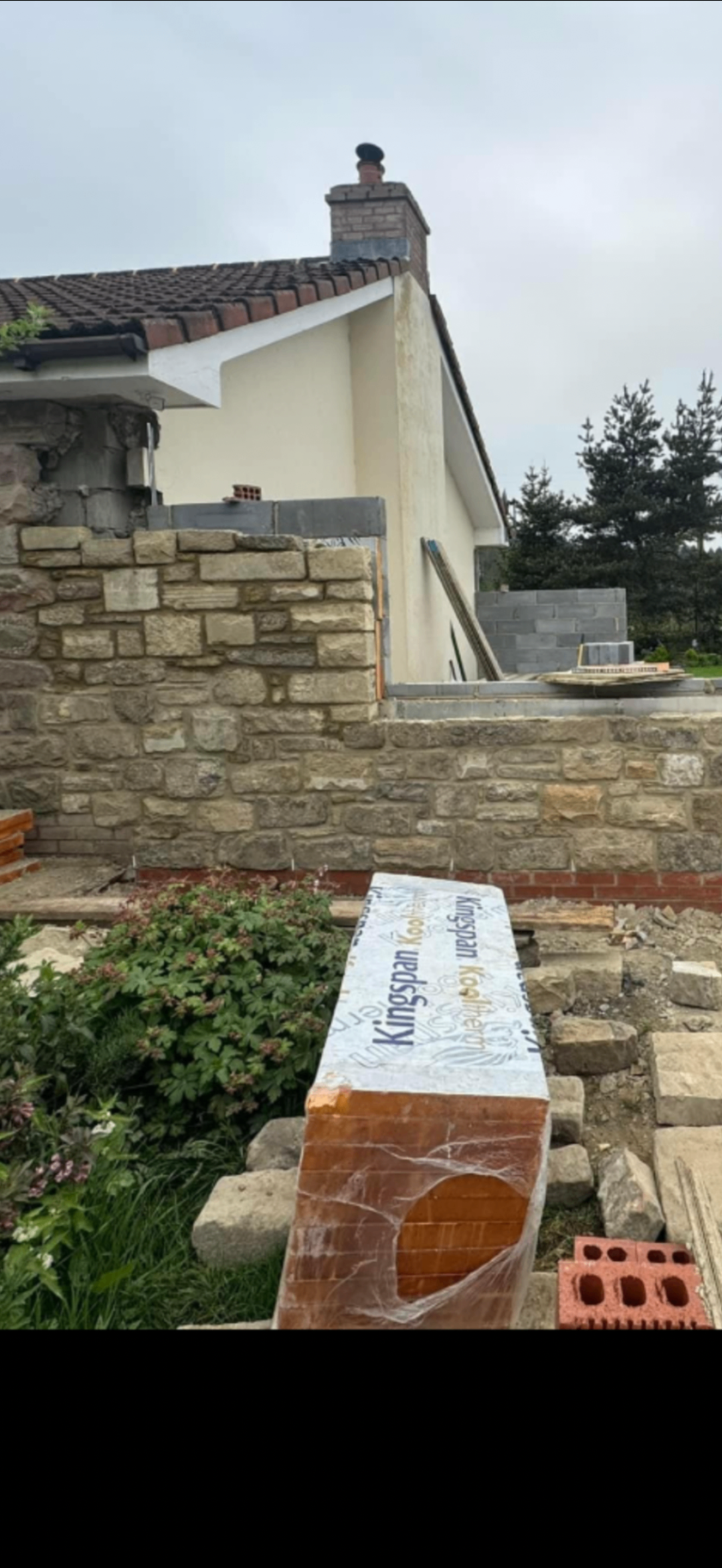 Natural stone boundary wall under construction beside an existing property in Northumberland.