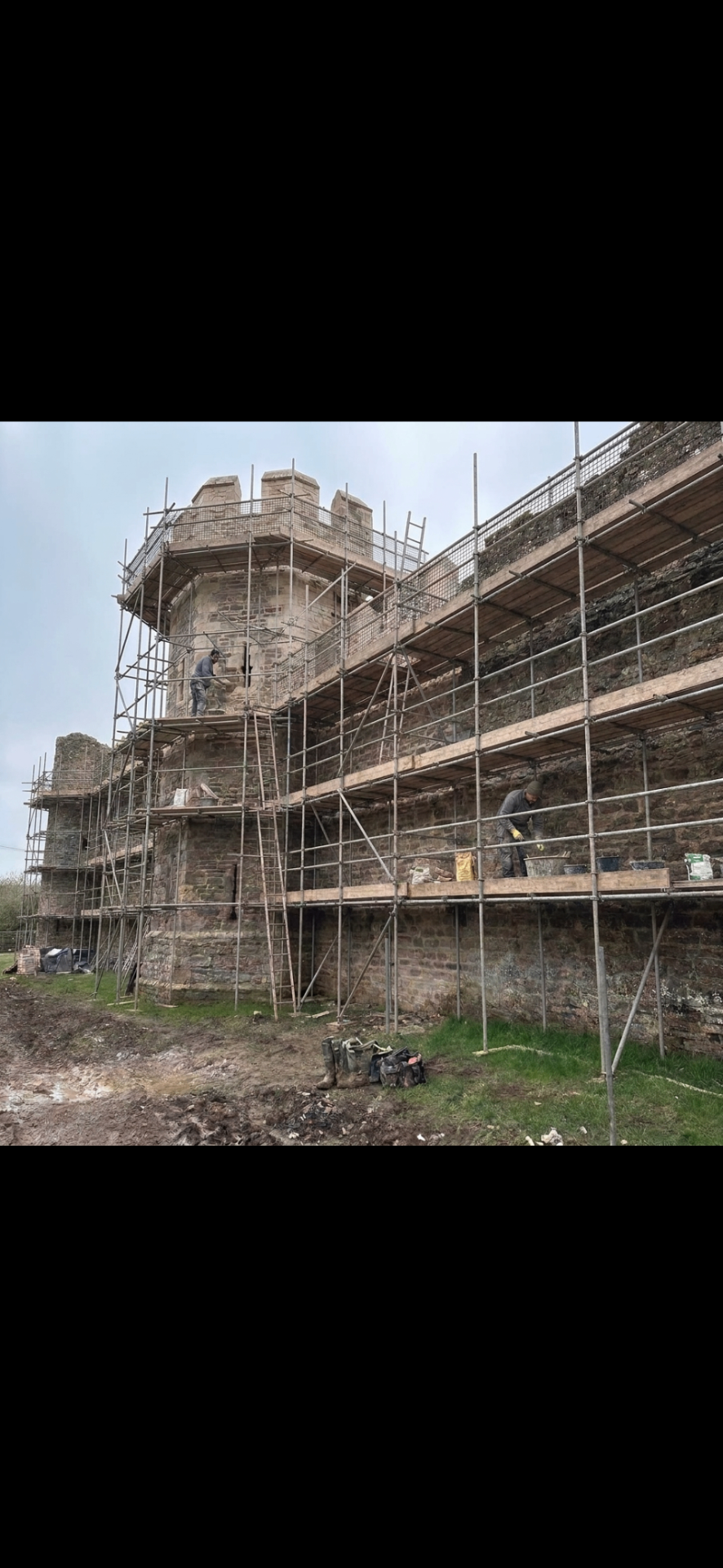 Historic stone castle wrapped in full scaffolding while Temple Builders craftsmen carry out specialist stone restoration and lime mortar repointing to the turret and curtain wall.