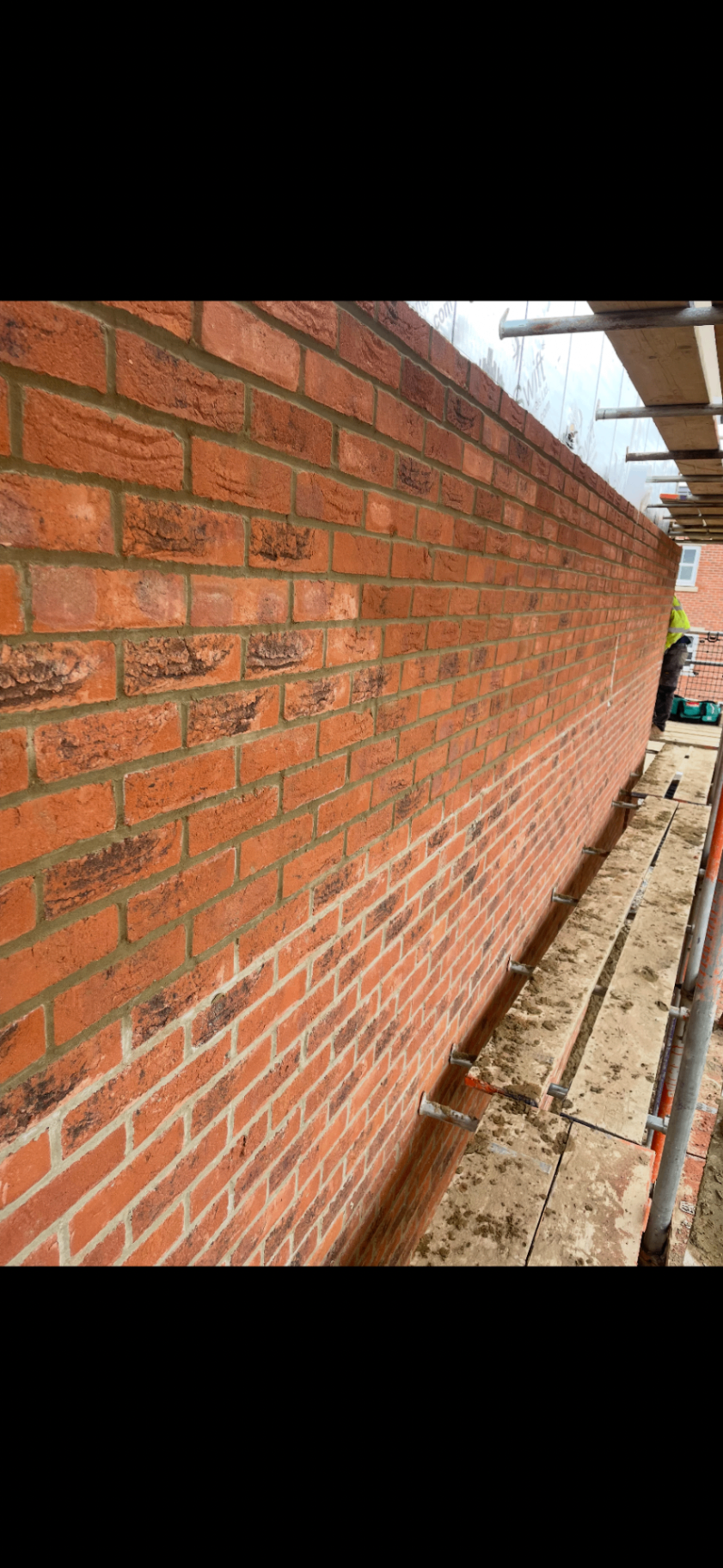 Close-up of finished red brick external walling and pointing on scaffold.