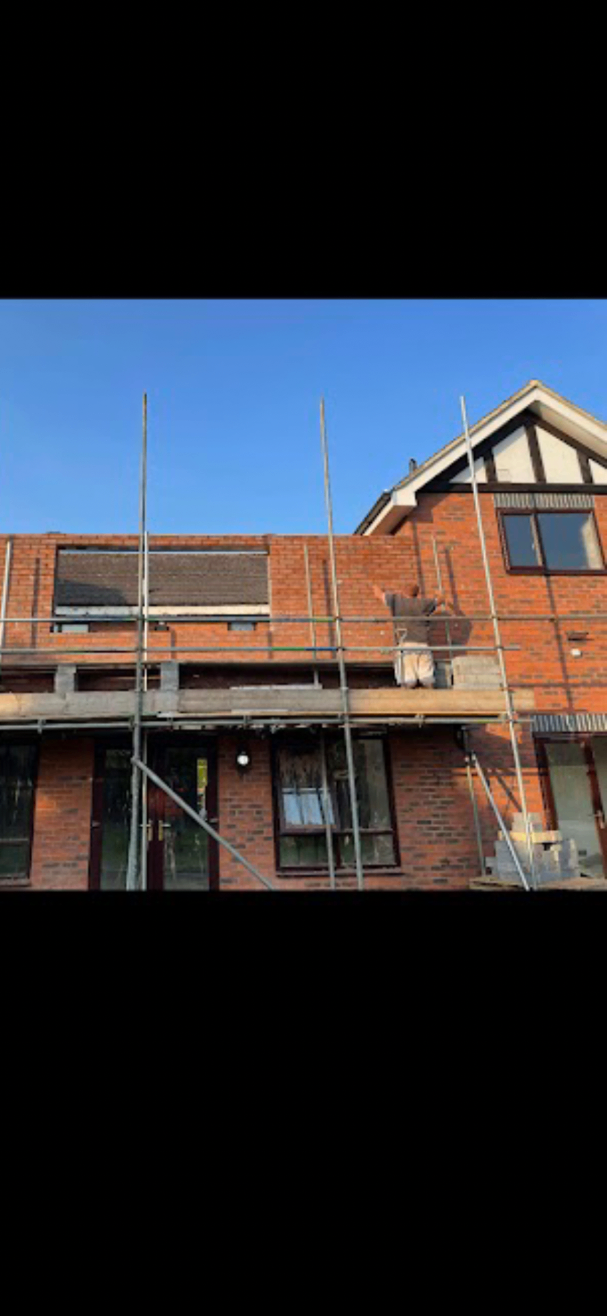 Two-storey brick residential extension under construction with scaffolding in place.