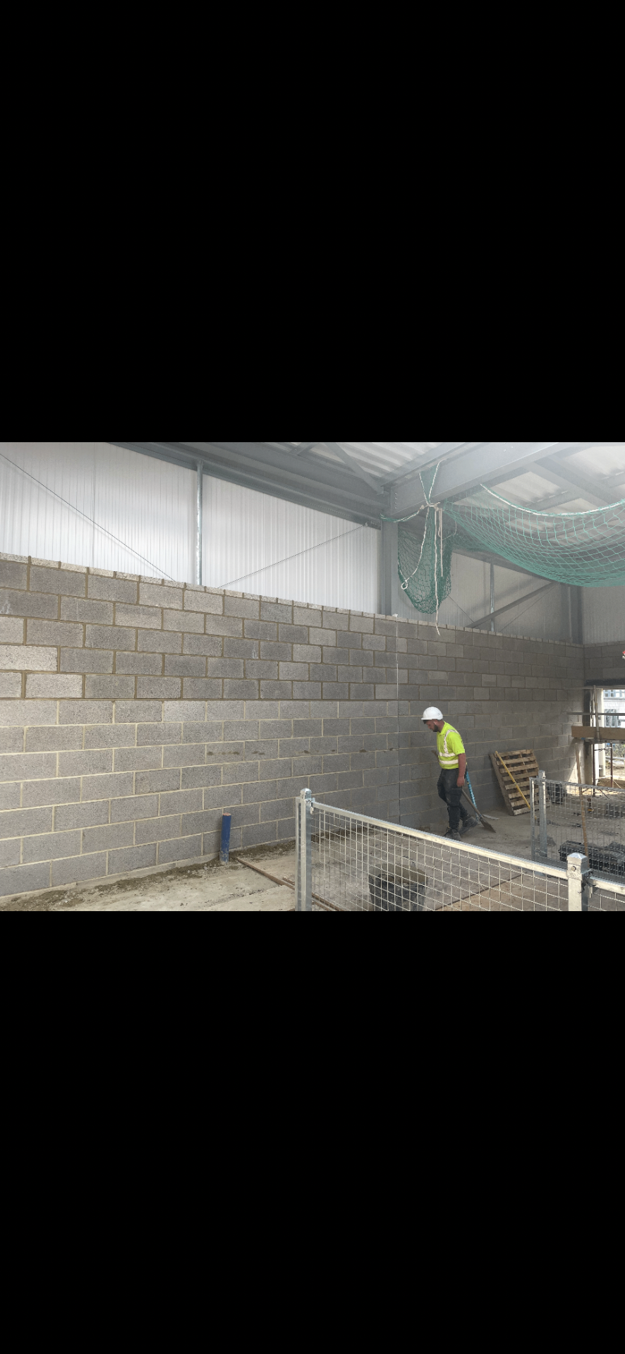 Industrial blockwork wall being built inside a steel-framed building shell.