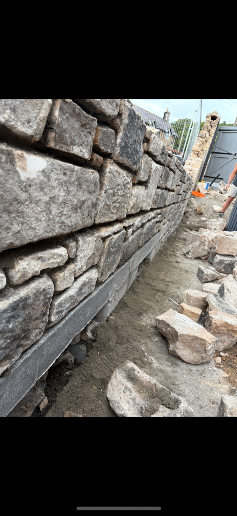 Close-up of a natural stone wall under construction showing the foundation and laid face stone.